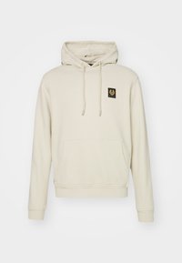 Beige huvtröja i mjukt tyg, med en ficka fram, dragsnören och en liten svart logotyp på bröstet.