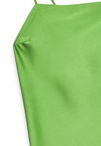 Grön satinkamisol med tunna band, med en slät yta och en lätt lyster. Designen är strömlinjeformad med minimal detaljer.