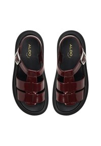 Maroon glossy sandals with three wide straps and a silver buckle. Black insole and textured rubber sole, showcasing a modern design.
