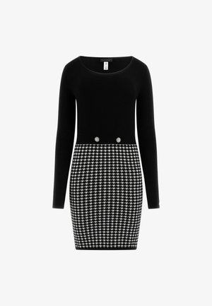 Schwarzes Langarmkleid mit figurbetontem Design. Der Oberteil besteht aus glattem Stoff, während der Rock ein strukturiertes Hahnentrittmuster aufweist. Zwei dekorative Knöpfe.