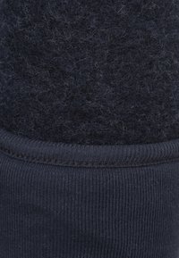 Donkerblauwe sok met een textuur en harige bovenkant en een ribbelige, gladde onderkant. Zacht materiaal met contrasterende afwerkingen.