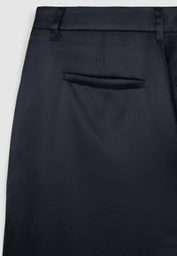 Schwarze Hose aus glattem Stoff mit taillierter Passform, ausgestattet mit einer einzelnen Gesäßtasche und gebügelt vorderen Falten.