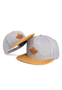 Siva snapback kapa s tan kože na robu, z rjavim usnjenim znakom na sprednji strani. Teksturna tkanina in nastavljiv pas.