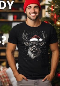 Black t-shirt displaying a graphic of a reindeer wearing sunglasses and a Santa hat, set against a snowy backdrop. Model smiles, hands in pockets.