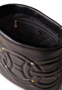 Black leather bag featuring a quilted design with gold-tone hardware accents. The interior has a zipper pocket and textured lining.