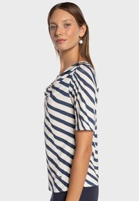 Granatowo-biała koszulka w paski z okrągłym dekoltem, krótkimi rękawami oraz marszczeniem z przodu. Wykonana z miękkiego, lekkiego materiału.