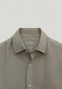 Hørskjorte i afdæmpet grå med en lille krave. Har fem knapper foran og vaskeanvisning indeni kraven. Blødt, tekstureret stof.