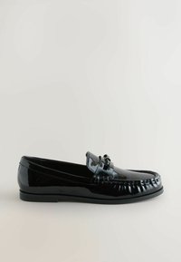 Sort patentlæder loafers med rund tå, dekorativ sløjfe akcent og syede detaljer langs kanten. Flad sål, slank profil.