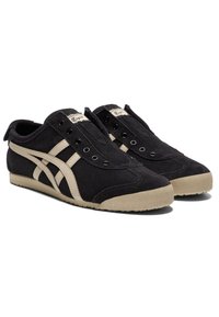 Černé sportovní boty z broušené kůže mají béžový retro proužkový design, zaoblenou špičku a gumovou podrážku s texturovaným gripem. Pět oček pro tkaničky.