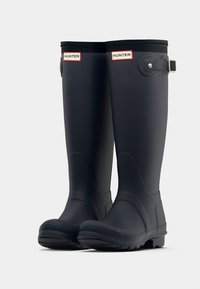 Bottes de pluie noires en caoutchouc, hautes jusqu'au genou, avec une finition lisse, un bout rond et un accent en boucle. Présentent une semelle texturée pour une meilleure adhérence.