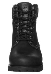 Bota de cuero negro con puntera redondeada, cordones prominentes, ojales reforzados y acentos de costura blanca en los laterales y el talón.