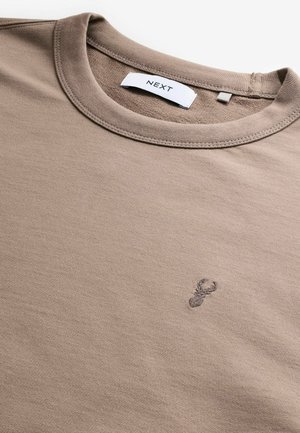 Tricou din bumbac bej cu guler rotund. Are un mic design brodat cu un homar pe piept. Include un eticheta de marcă pe guler.