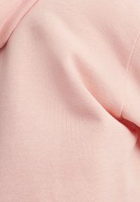 Lichtroze katoenen stof met een zachte textuur, voorzien van een gladde afwerking en subtiele ribbeldetails. Geschikt voor casual kleding of om te lagen.