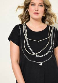 Schwarzes T-Shirt mit kurzen Ärmeln, das weiße Kettendesigns und Herzakzente in sich überlappenden, geschichteten Mustern auf der Vorderseite zeigt.