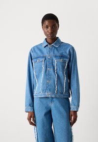 Giacca di jeans azzurro chiaro, con orli sfilacciati, chiusura con bottoni e due tasche sul petto. Maniche lunghe con design del colletto classico.