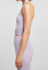 Top corto a coste in lavanda con una spallina a halter, design aderente e texture liscia; abbinato a una gonna a coste coordinata.