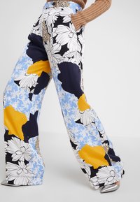 Wijdvallende pantalons met een bloemenprint in geel, blauw, zwart en wit. Gemaakt van een soepele stof met een comfortabele pasvorm.