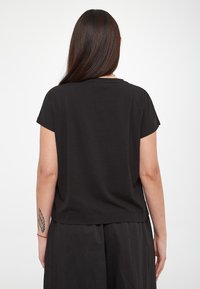 Maglietta nera a maniche corte con una vestibilità comoda, tessuto morbido, scollatura tonda e fondo pulito. Il retro presenta un design semplice e minimalista.