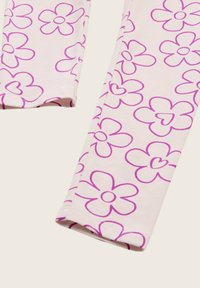 Katoenen legging in lichtroze met een herhaald patroon van grote, paarse bloemen met hartvormige centra. Glad, rekbaar textuur.