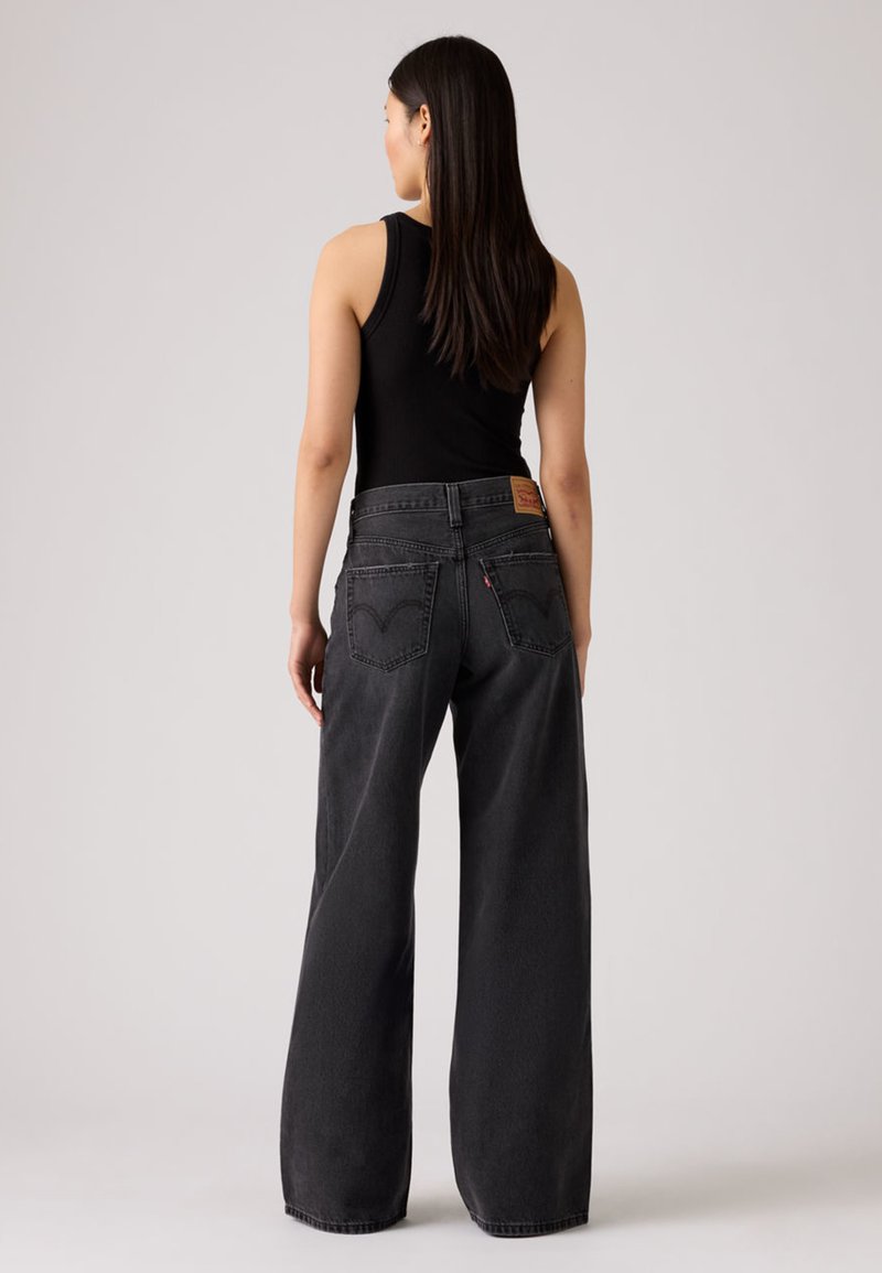 Jean noir à jambes larges en denim avec taille haute, deux poches arrière et une étiquette en cuir avec logo sur la ceinture.