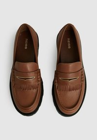 Brune læder loafers med et frynset design og guldhardware detaljer, med en kontrasterende sort gummisål og glat tekstur.