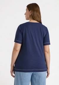 Camiseta de manga corta azul marino con cuello redondo, que presenta una textura suave y costuras en contraste a lo largo de las mangas y el dobladillo.