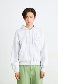 Hallide zip-up kapuutsviit, mis on valmistatud pehmest kangast, esiküljel taskud, millel on brodeeritud tekst "VABADUS on RAHU."