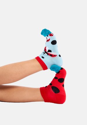 Calcetines coloridos: uno azul con mariquitas rojas y puntos negros, el otro rojo con puntos negros. Material de mezcla de algodón, de longitud hasta el tobillo, diseño divertido.