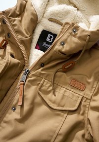 Veste beige avec doublure en polaire, fermeture éclair frontale, poche à rabat boutonnée, capuche avec cordon de serrage et étiquette de la marque "Blend" sur la poitrine et la tirette de la fermeture éclair.