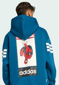 Blå hoodie i mjukt tyg, med en stor Spiderman-grafik på baksidan och vita tre-stripes detaljer på ärmarna.
