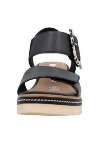 Sandale noire avec des larges brides, une boucle décorative avec un accent imprimé léopard, et une semelle plateforme beige avec des détails de couture.