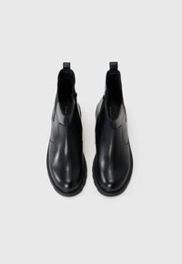 Bottines en cuir noir avec une finition lisse, des panneaux latéraux élastiques et un bout arrondi, avec un design de couture subtil et des languettes de tirage.