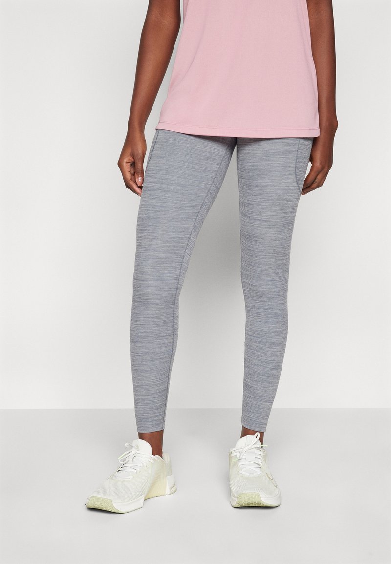 Leggings gris ajustados con una textura jaspeada, combinados con una camiseta de manga corta rosa y zapatillas deportivas blancas.