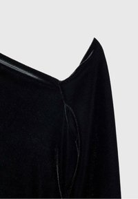 Vêtement en velours noir avec des plis nets et anguleux créant une forme d'épaule pointue sur un fond clair uni.