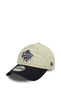 Baseball cap in cream cotton with a navy visor. Features embroidered "World Series" logo on the front and adjustable back strap.