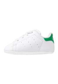 White leather sneaker with a smooth texture, rounded toe, green accent on the heel, and white rubber sole. Features perforated details.