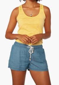 Keltainen hihaton toppi, jossa on teksturoidut hihnat, yhdistettynä vaaleansinisiin naruvaljaisiin shortseihin, joissa on rento istuvuus ja pehmeä kangas.