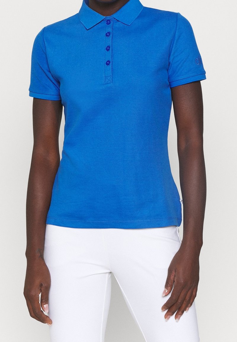 Polo bleu avec un col, comportant une patte de boutonnage à cinq boutons et des manches courtes. Le tissu semble lisse et léger.