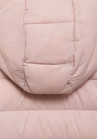 Jachetă căptușită dintr-un material moale de culoare roz pal, cu un model matlasat, având o glugă rotunjită și cusături contrastante. Textură netedă.