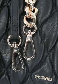 Borsa a tracolla in pelle trapuntata nera con hardware dorato, dotata di un dettaglio a catena spessa e due ganci a moschettone. Logo del brand visibile.