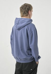Hoodie aus weichem blauen Baumwollstoff mit lockerer Passform, gerippten Bündchen und Saum. Verfügt über eine geräumige Kapuze und ein Kängurutaschen-Design.