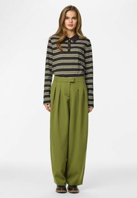 Paski koszulka polo z długim rękawem w kolorach brązowym, zielonym i białym; zestawiona z szerokimi, zielonymi spodniami z wysokim stanem. Miękka tkanina, luźny fason.