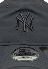Căciulă de baseball ajustabilă de culoare neagră, cu logo-ul brodat NY, textură netedă și vizor curbat. Prezintă un etichetă New Era care indică mărimea și stilul.