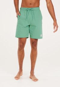 Groene zwembroek gemaakt van lichtgewicht stof, met een elastische tailleband met een trekkoord en een klein merklogo op de zoom.
