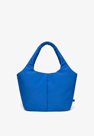 Sininen pehmeä kangaskassi leveillä pehmustetuilla kahvoilla ja yksinkertaisella, koristelemattomalla designilla valkoista taustaa vasten.