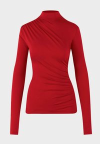 Rode langemouwen top met een hoge hals, met asymmetrische draping op één schouder en geraffineerde details aan de zijkant. Zachte, gladde stof.