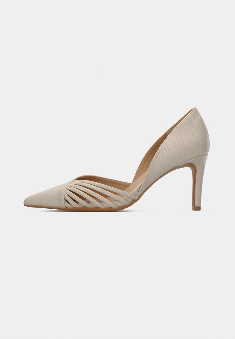 Zapato de tacón alto beige con punta afilada y parte superior texturizada. Presenta detalles entrecruzados en el lateral y un delgado tacón de aguja.