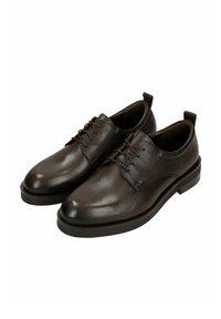 Scarpe in pelle marrone con una texture liscia, punta rotonda, lacci sottili e suole piatte e robuste. Presentano cuciture sottili e linguette posteriori per facilitare l'indossamento.