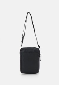 Svart nylon crossbody-väska med rektangulär form, framficka med dragkedja, justerbar rem och logotyp präglad på framsidan.