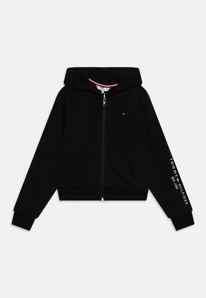 Czarna bluza z kapturem zapinana na zamek, wykonana z miękkiego materiału, z kapturem, ściągaczami na mankietach oraz napisem „TOMMY HILFIGER EST. 1985” w białym kolorze na rękawie.